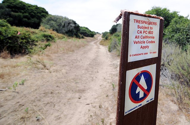 No trespassing sign beside a dirt road