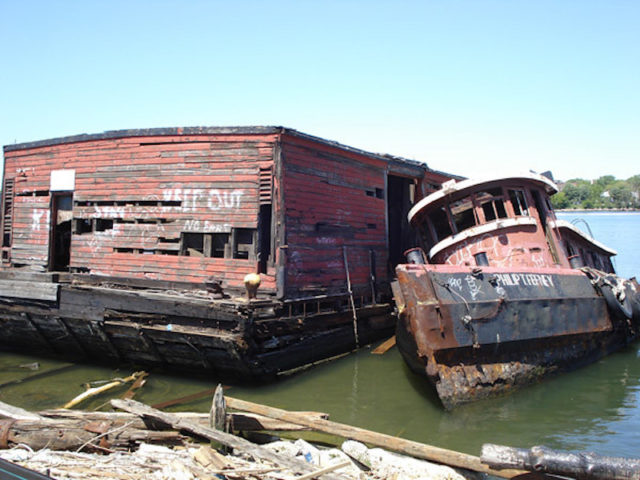 Tugboat leaning against a larger boat at the Staten Island Tugboat Graveyard