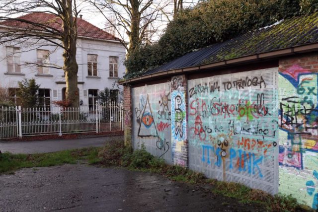 Graffiti-covered shed with a house in the background