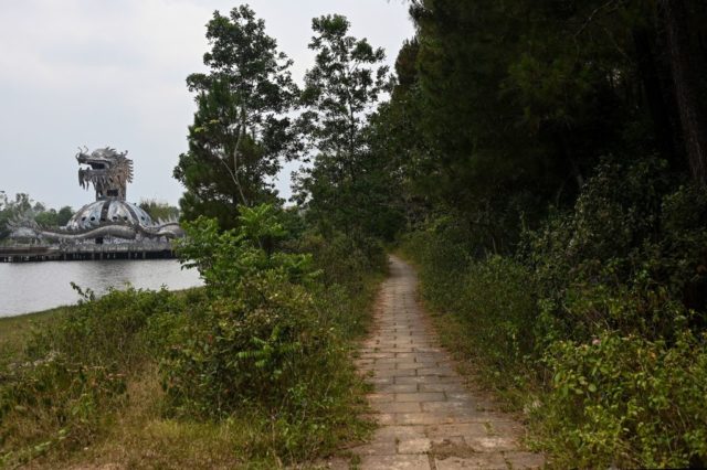 Dirt pathway with the Hồ Thuỷ Tiên aquarium in the distance