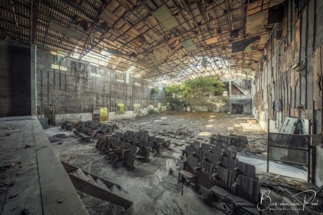 A theatre sits in ruins with roof caving in.