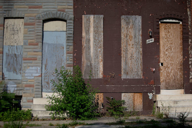 Two boarded up houses along a street