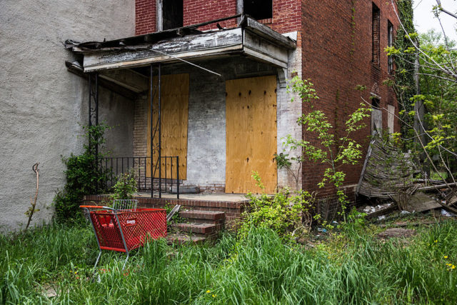 Shopping cart outside of a boarded up house