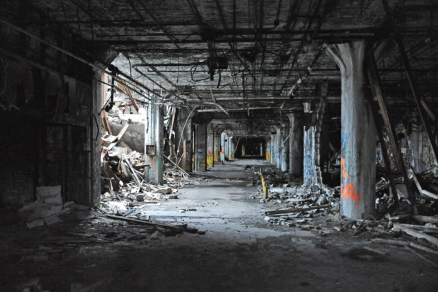 Debris-filled room dimly lit by a hole in the wall