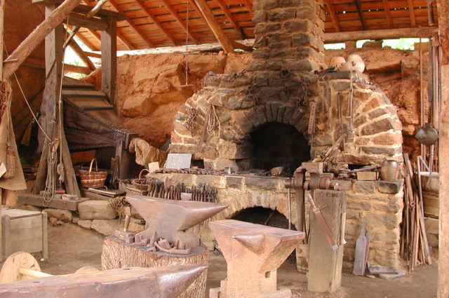 Stone fireplace and tools inside Guédelon Castle
