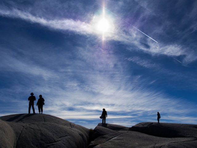 Four tourists standing on the black rocks at Peggy's Cove