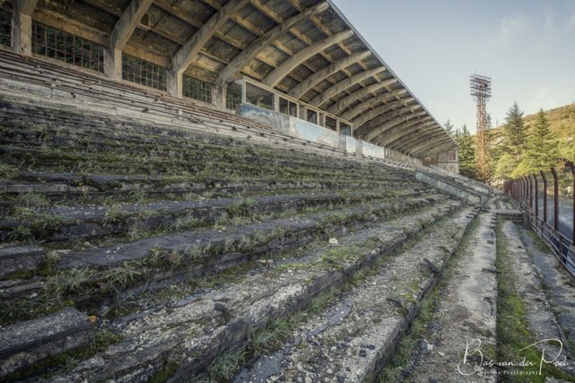 Grass growing over rows of bleachers at a stadium