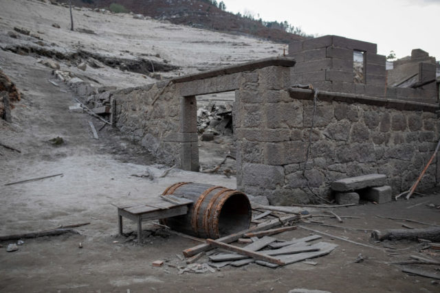 Wooden barrel buried in the mud outside of a roofless building