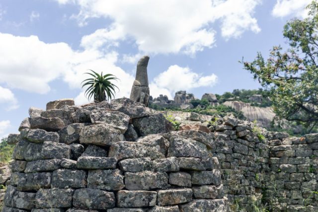 A soapstone bird carving sits on top of a pile of stone bricks