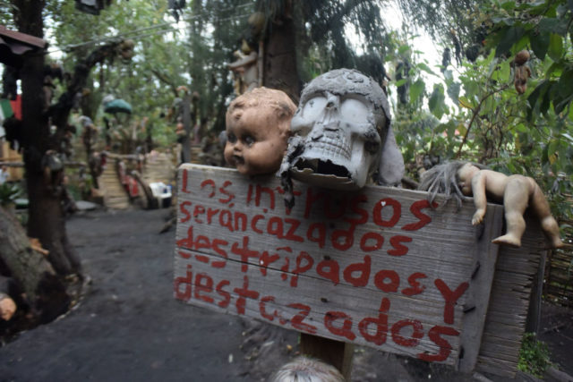 Skull and doll head atop a wooden sign