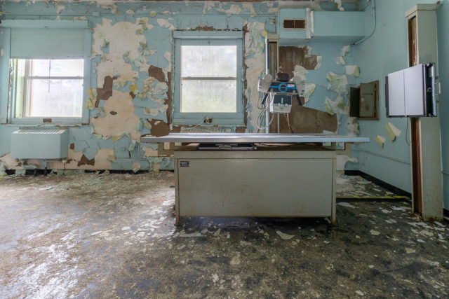 Table and medical equipment in a room with paint peeling off the walls