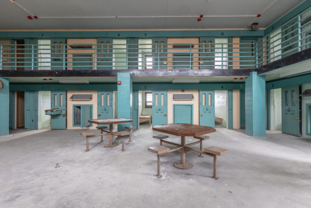 Two communal tables surrounded by prison cells