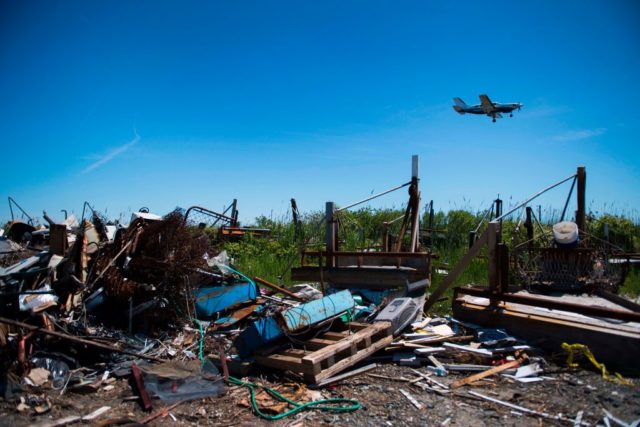 Airplane flying over debris scattered across a beach