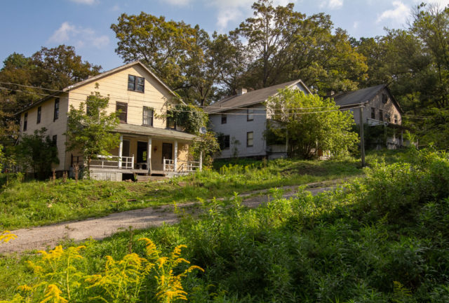 Three houses along a dirt road in Yellow Dog Village