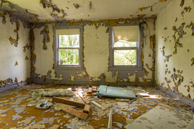 Large room filled with debris and with paint peeling from the walls