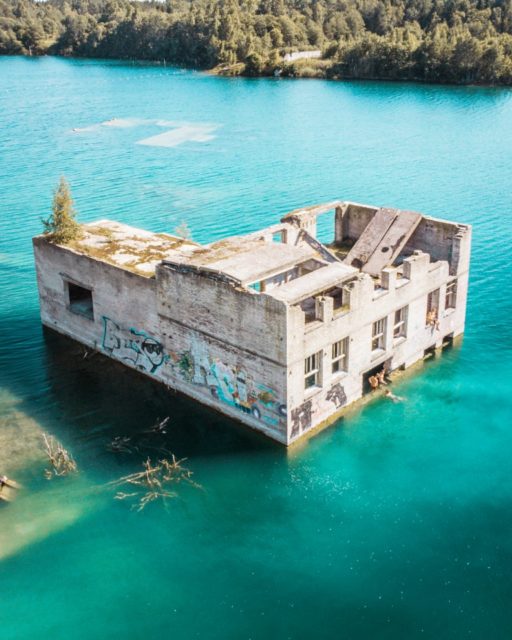 An aerial view of the abandoned Rummu quarry standing in the crystal blue waters of the lake