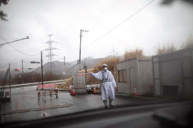 Guard standing at a checkpoint at the exclusion zone in Futaba