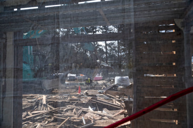 Man standing among the remains of a ruined house in Futaba