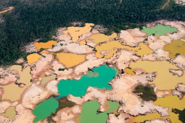 Aerial shot of a forest with large areas of brown dirt and discolored ponds