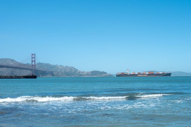 Container ship traveling over the water towards the Golden Gate Bridge.