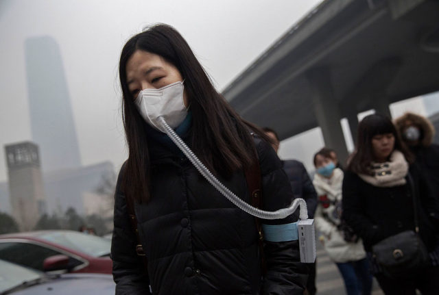 Woman wearing a mask with an attached tube leading to a band on her arm.