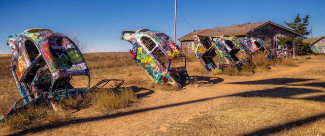 Row of Volkswagen Beetles spray painted and stuck into the ground nose first.