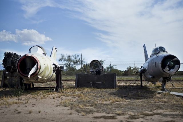 Damaged Mikoyan-Gurevich MiG-15 and Mikoyan MiG-29 parked in front of a fence