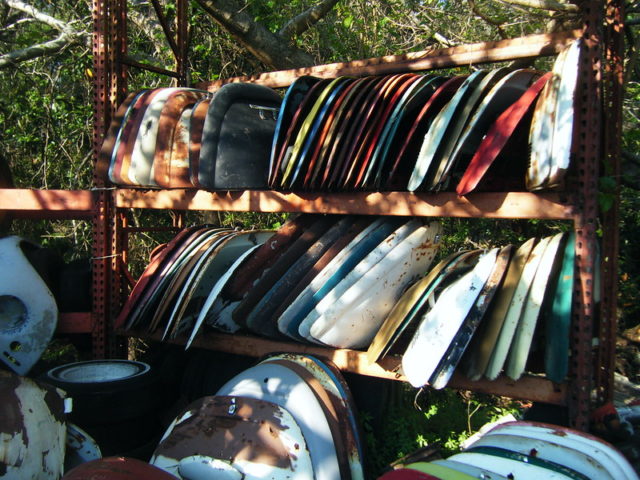 Colorful Volkswagen parts organized on racks in the middle of a forest.