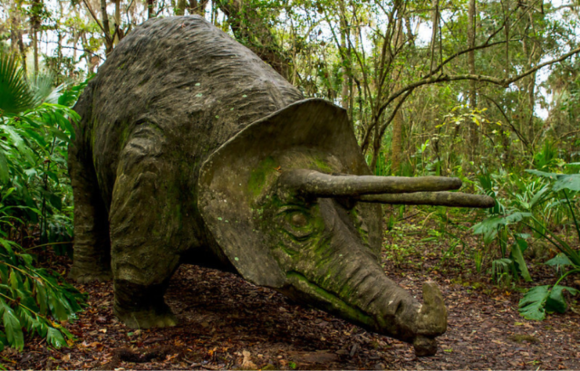 Statue of a Stegosaurus in the middle of a forest
