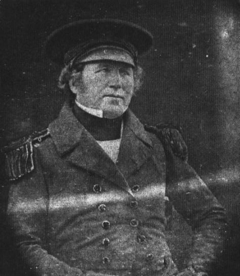 Francis Crozier wearing a jacket and hat while sitting for a portrait.