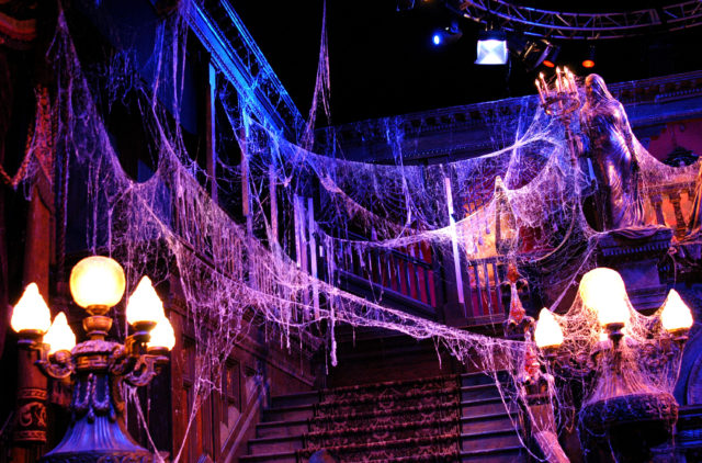 Cobwebs hanging from chandeliers with a staircase