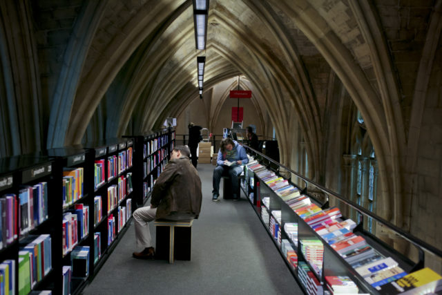 People sitting on stools beside bookcases in a domed hallway