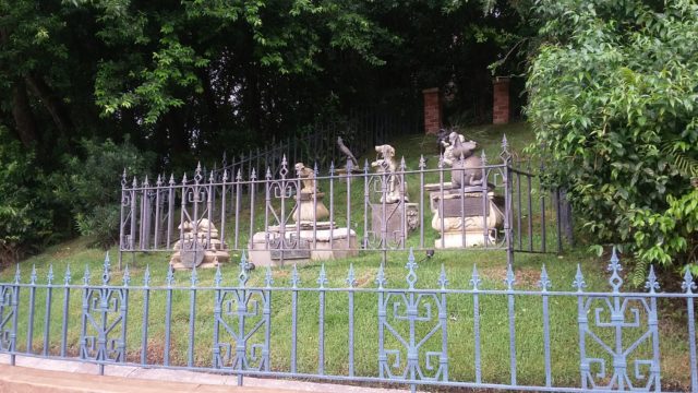 Gravestones on a hill behind an iron fence