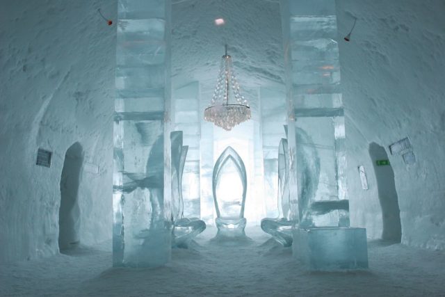 Chairs made from ice positioned below a chandelier