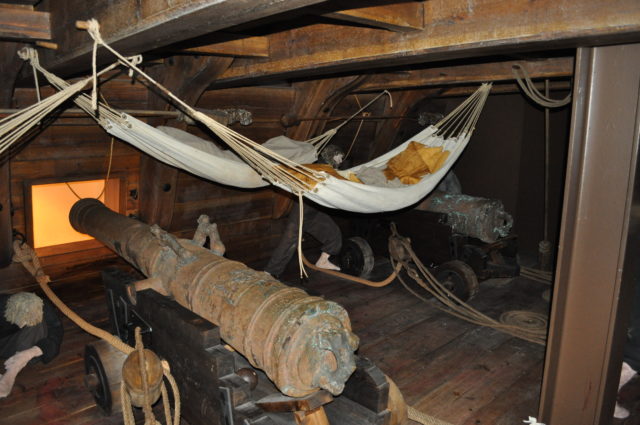 Hammocks are swung above cannons in a display of the ship's deck