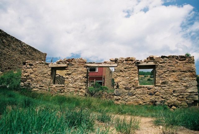 Half destroyed brick building in a patch of green grass.