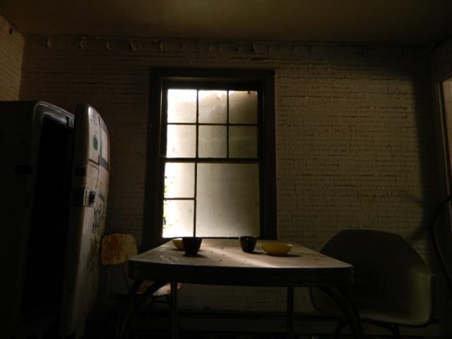 A kitchen table with a fridge in an abandoned home