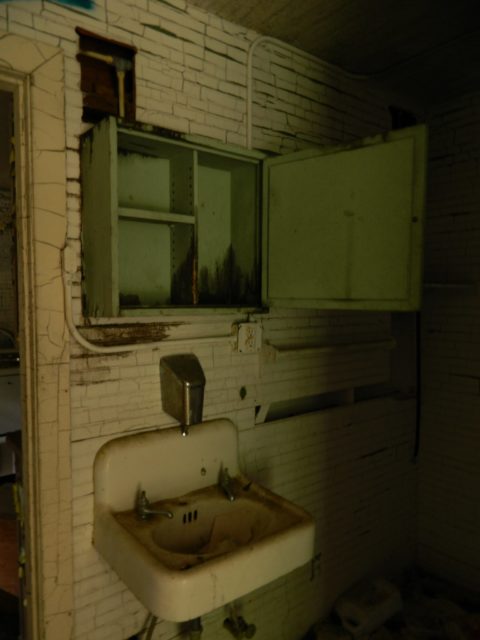A sink and medicine cabinet inside an abandoned bathroom
