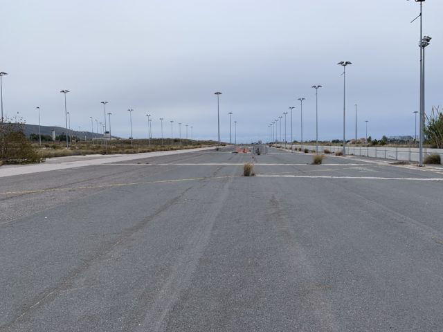 Pavement runway with lights running down either side and abandoned materials in the middle of it.