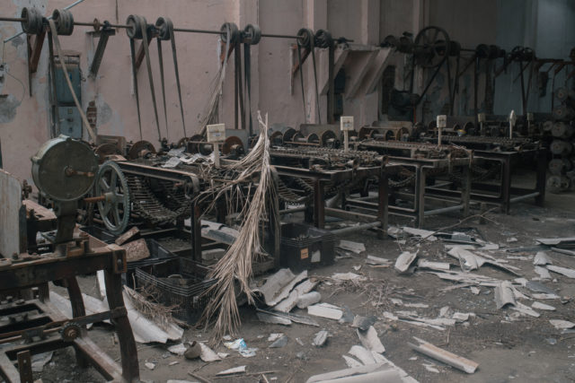 Factory machines sit rusted and abandoned, surrounded by debris