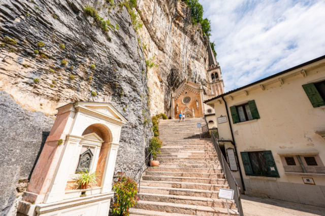 Stone stairway leading up to the Santuario Madonna della Corona with a tall rock face on the left.