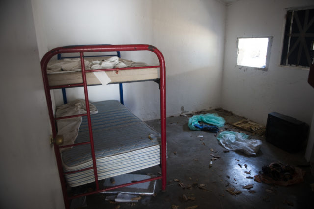 A red bunkbed sits in an abandoned, filthy room.