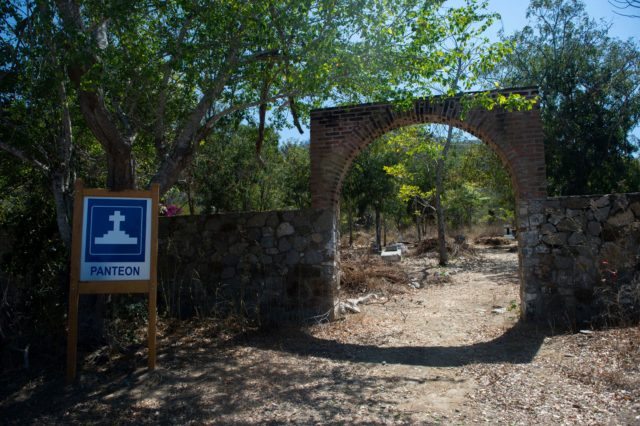 An archway over a dirt path with a sign out front