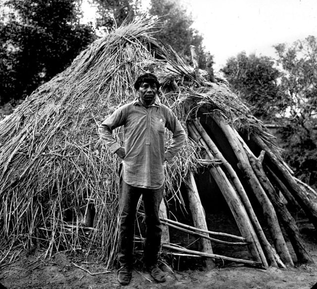 A man photographed in front of a stick structure