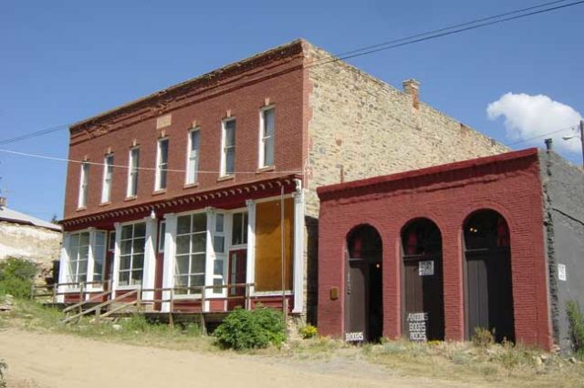 Masonic Temple, a brick building with a red facade with large bay windows, beside a smaller red building with three doors.