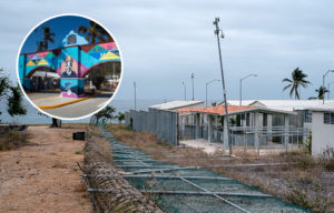 A prison structure with a fallen fence, as well as a colorful archway with Nelson Mandela's face