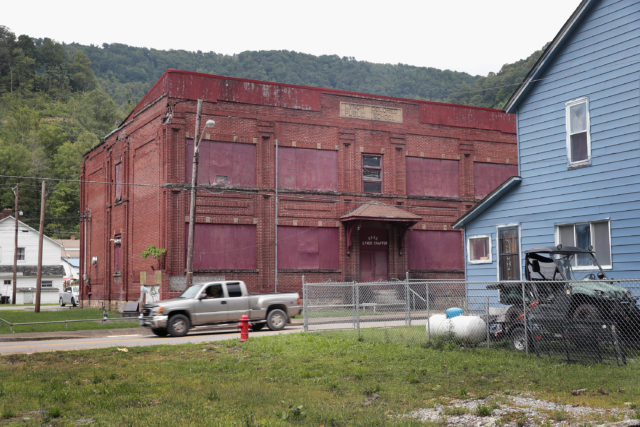 Pickup truck driving past a boarded-up building