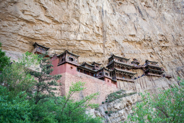 VIew looking up at the Hanging Monastery of Mount Heng, a detailed building set into a cliff face.
