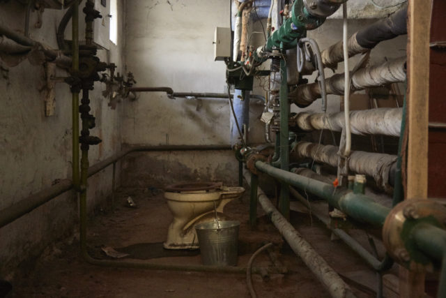 A toilet in a room with exposed piping