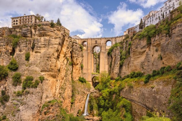 Bridge carved from rock overtop of a small waterfall.